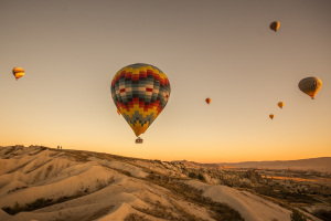 The hot air balloons over the hills and the fields during sunset in Cappadocia, Turkey